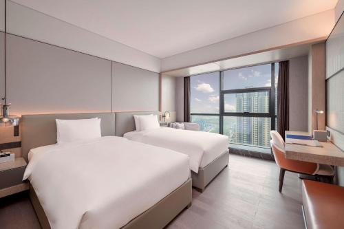 a hotel room with two beds and a desk at Doubletree By Hilton Xian Fengdong in Xi'an