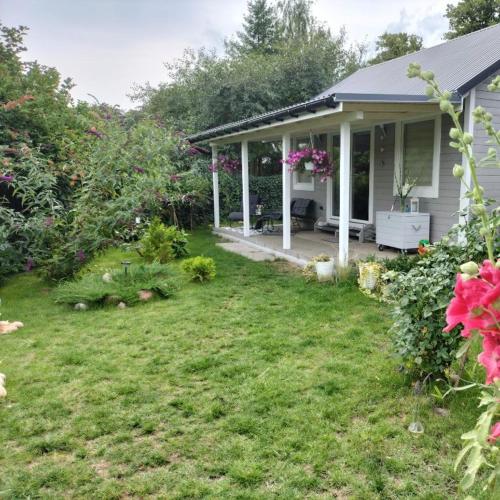 a small house with a yard with flowers at Domek nad jeziorem, a morze w gratisie in Wisełka
