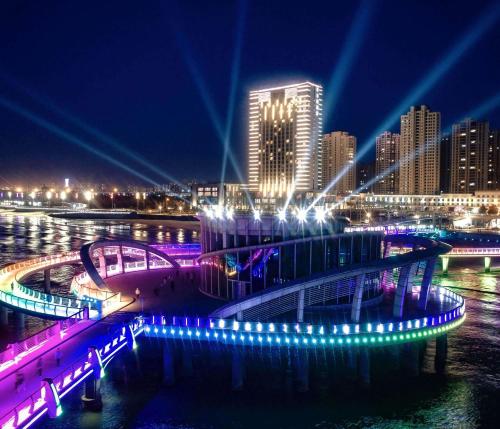 a bridge over a river with a city at night at Hilton Yantai Golden Coast in Yantai