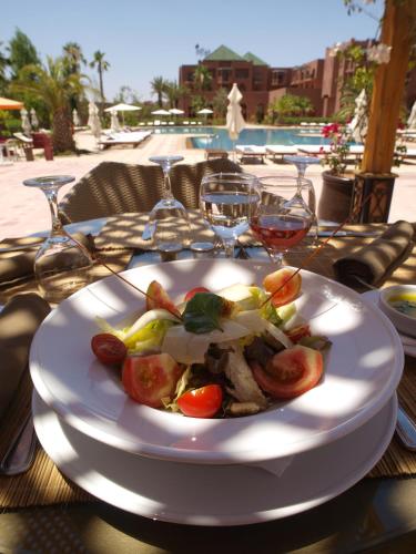 a plate of food on a table with wine glasses at Palm Plaza Marrakech in Marrakech