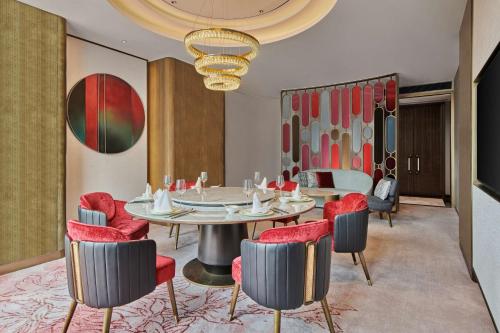 a dining room with a table and red chairs at Hilton Yancheng in Yancheng
