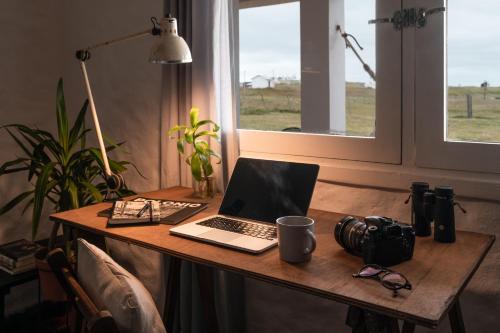 una scrivania con un computer portatile e una macchina fotografica di Palacio de la luna, casa única frente al mar a Cabo Polonio
