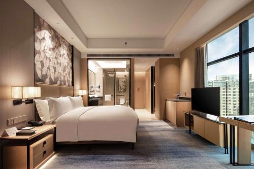 a hotel room with a bed and a television at Doubletree By Hilton Yangzhou in Yangzhou