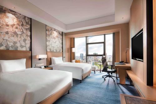 揚州市にあるDoubletree By Hilton Yangzhouのベッド2台とテレビが備わるホテルルームです。