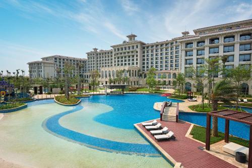 a large hotel with a large pool in front of a building at Hilton Haikou Meilan in Haikou