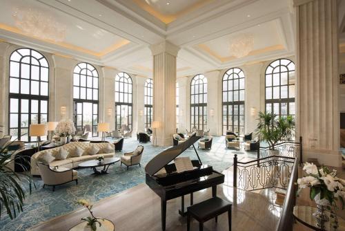 a large living room with a piano and a living room withwindows at Hilton Haikou Meilan in Haikou