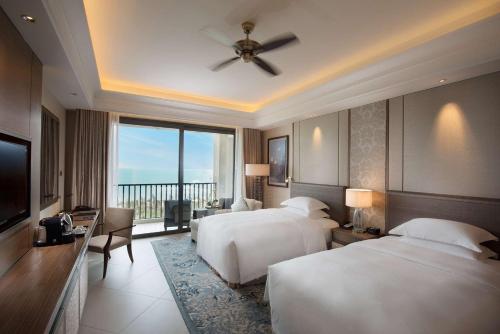 a hotel room with two beds and a television at Hilton Haikou Meilan - Beachfront Hotel in Haikou