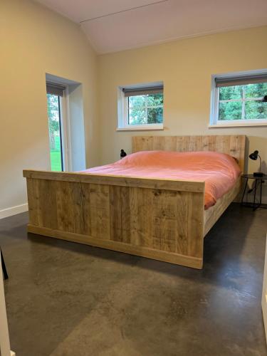 ein Schlafzimmer mit einem großen Holzbett in einem Zimmer mit Fenstern in der Unterkunft Erve Volthebrook in Rossum