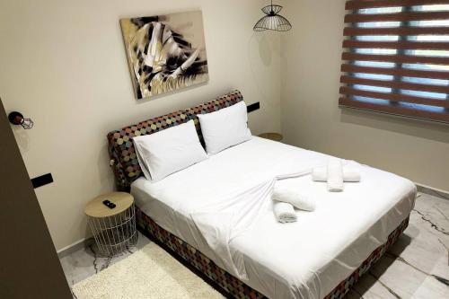 a bedroom with a bed with white sheets and pillows at Luxury Home with Garden in the Suburbs in Kalamata