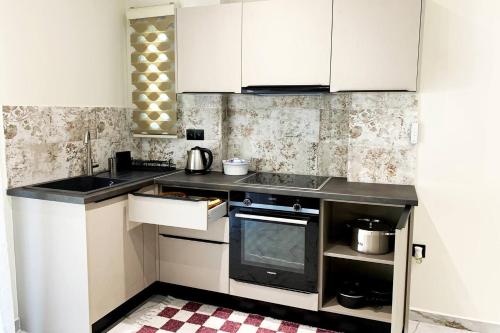 a kitchen with white cabinets and a sink and a stove at Luxury Home with Garden in the Suburbs in Kalamata