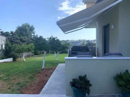 a porch of a house with a couch and an umbrella at Luxury Home with Garden in the Suburbs in Kalamata