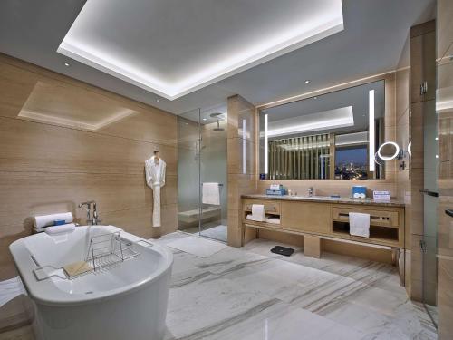 a bathroom with a bath tub and a mirror at Hilton Beijing Tongzhou in Beijing