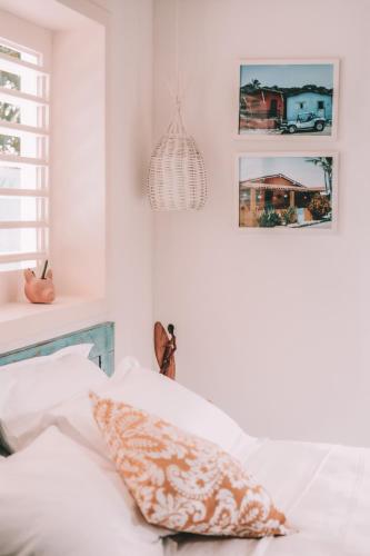 a bedroom with white walls and a bed with white pillows at Cactus Lodge Pipa in Pipa