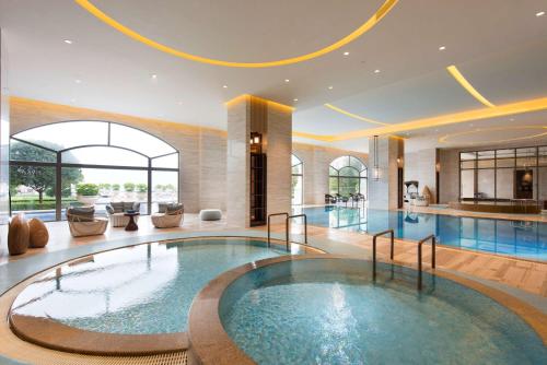 a large pool in a hotel lobby with a swimming pool at Hilton Yuxi Fuxian Lake in Chengjiang