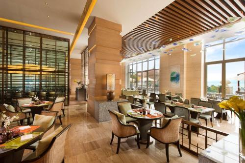 um restaurante com mesas, cadeiras e janelas em Hilton Yuxi Fuxian Lake em Chengjiang