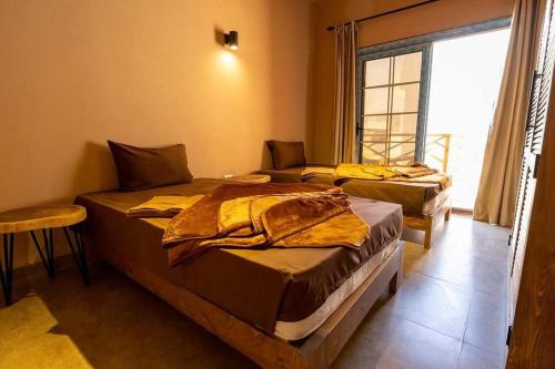 two beds in a room with a window at The Sand apartment in Dahab