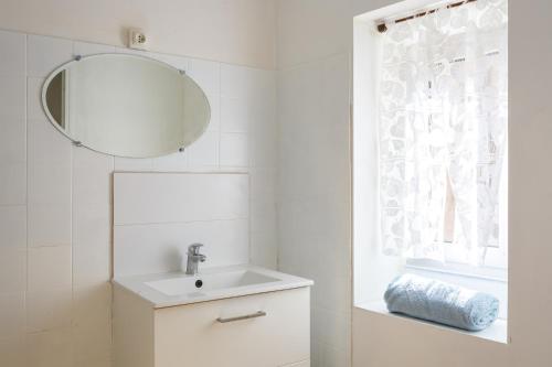 a white bathroom with a sink and a mirror at Cosy Gîte in Gabian with Beautiful River and Vineyard Views in Gabian