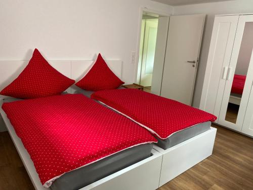 Una cama roja con almohadas rojas encima. en Ferienwohnung am Liederbach, en Waldshut-Tiengen