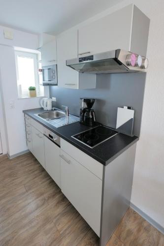 a kitchen with white cabinets and a black counter top at Elena Kempf Haaratelier & Guesthouse in Braunfels