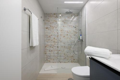 a white bathroom with a shower and a toilet at RENOVADO APARTAMENTO 1º LINEA DE MAR in San Agustin