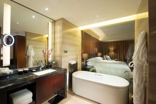 a bathroom with a bath tub and a bed at Hilton Shijiazhuang in Shijiazhuang