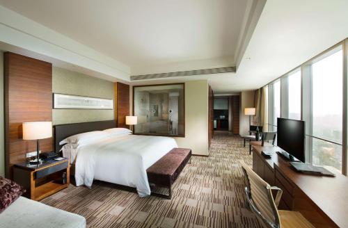 a hotel room with a bed and a flat screen tv at Hilton Shijiazhuang in Shijiazhuang
