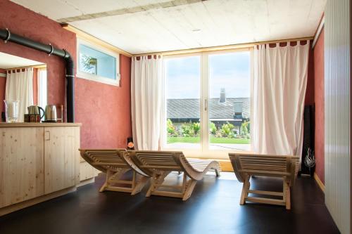 - un salon avec une table, des chaises et une grande fenêtre dans l'établissement Retreat Lodge Schürmatt -Leben wie SchweizerInnen, à Günsberg  