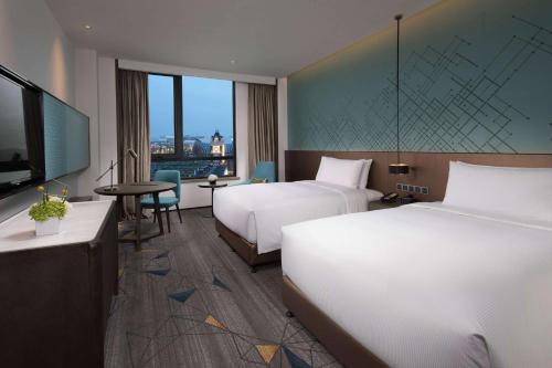 a hotel room with two beds and a flat screen tv at Doubletree By Hilton Qingdao Oriental Movie Metropolis in Huangdao
