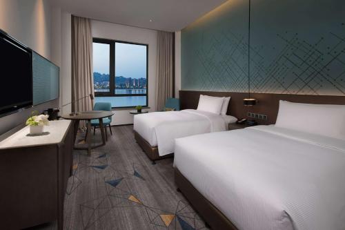 a hotel room with two beds and a flat screen tv at Doubletree By Hilton Qingdao Oriental Movie Metropolis in Huangdao
