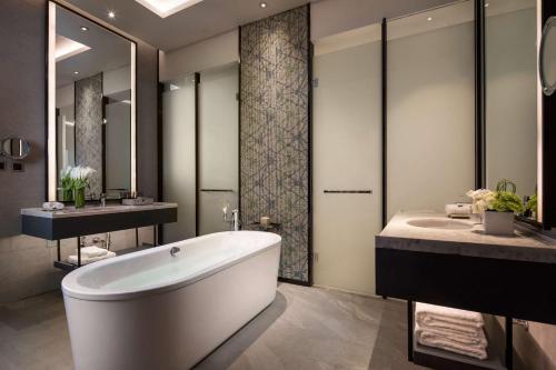 a bathroom with a tub and two sinks and a bath tub at Doubletree By Hilton Qingdao Oriental Movie Metropolis in Huangdao