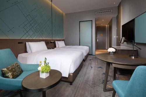 a hotel room with a large bed and two tables and chairs at Doubletree By Hilton Qingdao Oriental Movie Metropolis in Huangdao