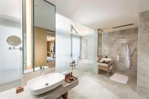 uma casa de banho com um lavatório branco e uma banheira em Conrad Hangzhou Tonglu em Yinzhu