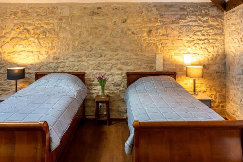 twee bedden in een kamer met een stenen muur bij Moulin du Fontcourt in Chasseneuil-sur-Bonnieure