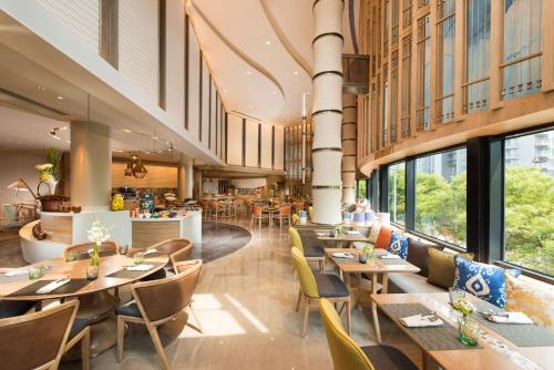 a restaurant with wooden tables and chairs and windows at Hilton Beijing - Close to Capital Airport Express Subway & Liangma River located in the Embassy area in Beijing