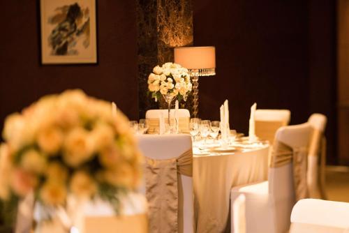 a table with white tables and chairs with flowers on it at Hilton Beijing - Close to Capital Airport Express Subway & Liangma River located in the Embassy area in Beijing
