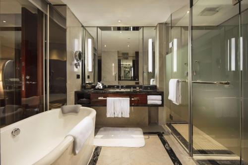 a bathroom with a tub and a glass shower at Hilton Foshan in Foshan