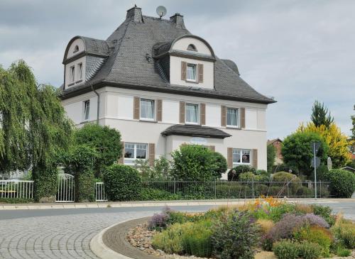 a large white house with a gray roof at Elena Kempf Haaratelier & Guesthouse in Braunfels