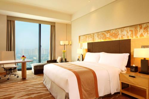 a hotel room with a large bed and a desk at DoubleTree by Hilton Hangzhou East in Hangzhou