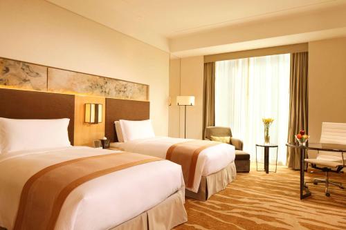 a hotel room with two beds and a window at DoubleTree by Hilton Hangzhou East in Hangzhou