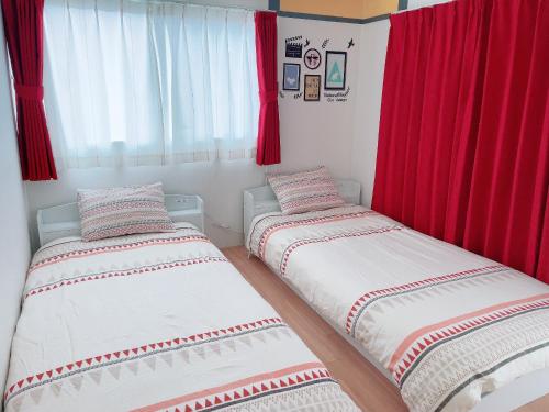 duas camas num quarto com cortinas vermelhas em Takamatsu-house201 em Shimminatomachi