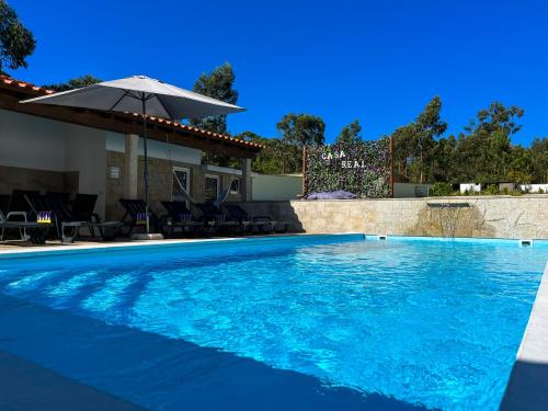 a swimming pool with an umbrella next to a house at Casa Real - Royal Villa in Esposende