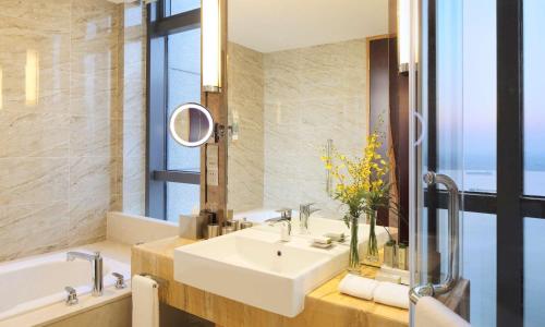 a bathroom with a sink and a tub and a mirror at DoubleTree by Hilton Wuhu in Wuhu