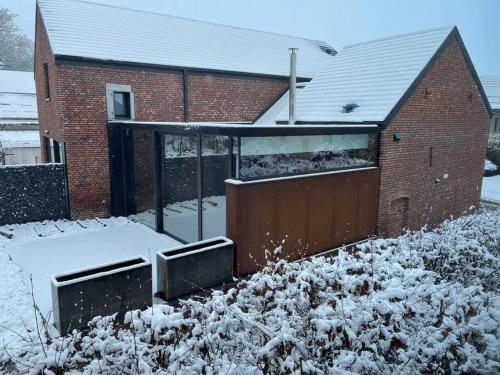 a building with snow on the ground next to a garage at Gîte 'Au bout du Tige' in Braives