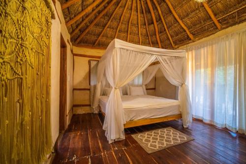 a bedroom with a bed with a canopy in a room at SelvaLuz Tulum Resort & Spa in Tulum