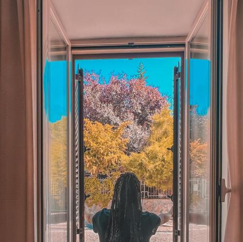 Una mujer mirando por la ventana con los brazos abiertos en B&B La Rosa 
