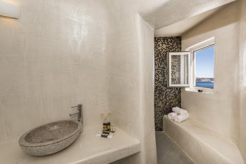 a bathroom with a large tub and a window at Ambition Suites in Oia