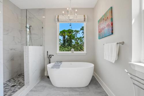 a white bathroom with a tub and a window at Fruitcakes in St. George Island