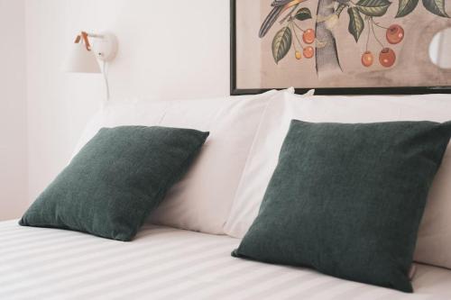 ein weißes Bett mit zwei grünen Kissen darauf in der Unterkunft Insidewonderfulcomo in Como