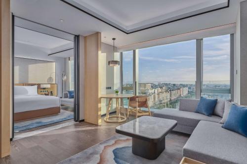 a bedroom with a bed and a living room with a view at Doubletree By Hilton Shenzhen Airport in Bao'an