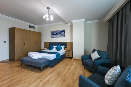 ドーハにあるSaray Musheireb Hotel and Suitesのベッド1台と椅子2脚が備わるホテルルームです。